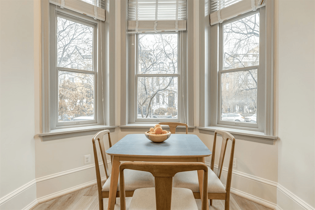 a dining room with three windows and a table and chairs